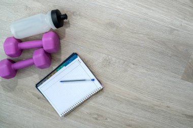 Dambıl şeklinde güzel spor aletleri ve dambıllar yerde yatıyor. Arka planda spor ekipmanı kavramı