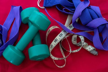 Spor kıyafetleri ve halterler şeklinde ilginç spor ekipmanları pembe bir paspasın üzerinde. Spor konsepti. Spor malzemeleri konsepti