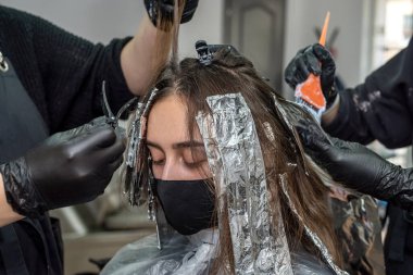 Nitelikli bir renk uzmanı bir güzellik salonunda sıradan bir müşterinin saçını boyar. Müşteri saç boyama kavramı