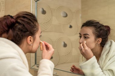 Genç bir kız, akşamları banyoda, ev kıyafetleriyle makyaj yapıyor. Kadın makyaj konsepti