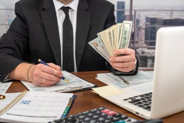 Ofis kıyafetleri içindeki bir adam, Birleşik Devletler 'in vergi formları üzerinde çalışır ve iş için hesaplamalar yapar. Vergi formu kavramı 1040 dolar.