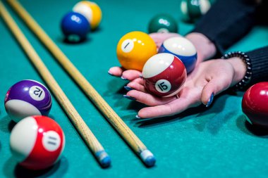 Siyah elbiseli güzel kadın ellerini elinde bir ıstaka tutarken ve bilardo katmanını deliğe sokmaya çalışırken görebilirsiniz. Bilardo sporu oyun konsepti