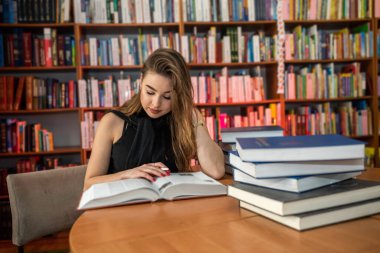 Mezuniyetten sonra genç bir öğrenci yeni bilgiler öğrenmek için kütüphaneye gelir. Kütüphanedeki kız öğrenci konsepti.