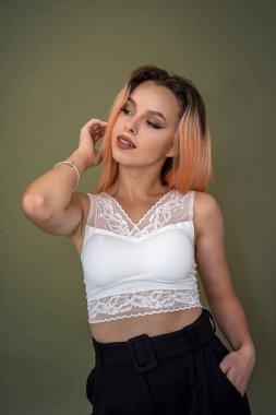 Beyaz bluzlu ve siyah pantolonlu güzel bir genç kız koyu yeşil arka planda güzel duruyor. Arkaplanda kız konsepti