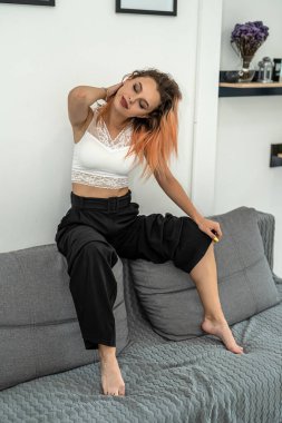 İşten sonra kanepede dinlenen bir kızın portresi, evdeki kanepede sıcak bir şekilde oturuyor. Rahat bir kanepe ve dinlenme konsepti