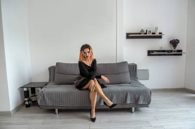 Zarif elbiseli güzel kız yeni bir kanepede dinleniyor. Kız kanepede ziyaret ediyor.