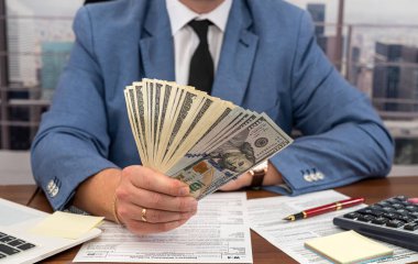 Ofis kıyafetleri içindeki bir adam, Birleşik Devletler 'in vergi formları üzerinde çalışır ve iş için hesaplamalar yapar. Vergi formu kavramı 1040 dolar.