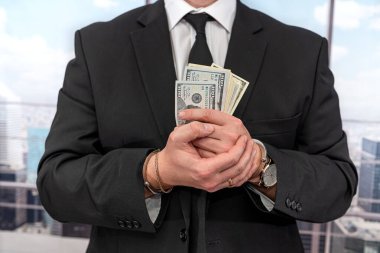 Pahalı siyah takım elbiseli bir işadamı, yasadışı para aklayan kelepçe takıyor. Yasadışı kazanç kavramı