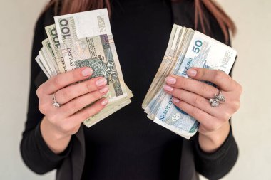 Genç kadın mutlu bir şekilde gülümsüyor, şehirde Polonya zloti paraları tutuyor. Cilalı banknotları olan başarılı kadın kavramı