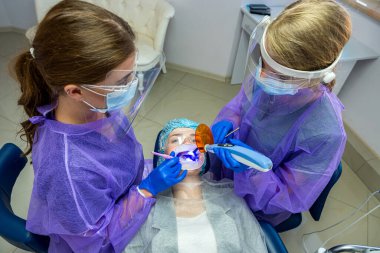 Diş kliniğinde önlüklü ve turuncu gözlüklü güzel bir kız. Diş tedavisi kavramı.