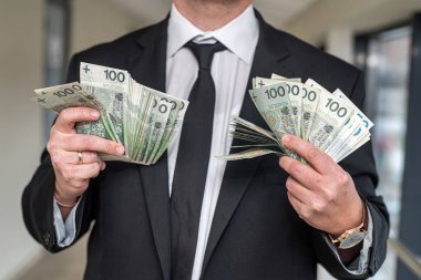 Polonya 'nın yeni zloti paraları takım elbiseli bir iş adamının elinde. Büyük ve küçük işletme kavramı