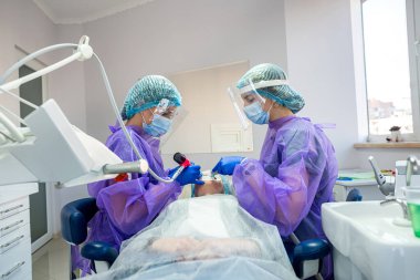 Diş muayenehanesinde, dişçi ve asistanı yüksek yirmilik dişleri çıkarmak için bir ameliyat yaparlar. Diş hekimliğinde cerrahi kavramı