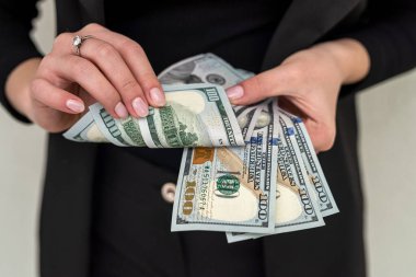 Klasik takım elbiseli güzel bir genç kız elinde yüklü miktarda para tutuyor. İş ve gelir kavramı