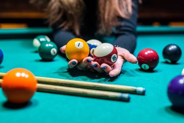 Bilardo salonundaki geniş bir masada bilardo toplarını kovalayan genç ve güzel bir kızın elleri. Bilardo konsepti