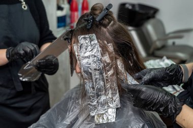 Güzel esmer, salgın sırasında sarışın olmak için salona geldi. Güzellik salonunda saç aydınlatma konsepti