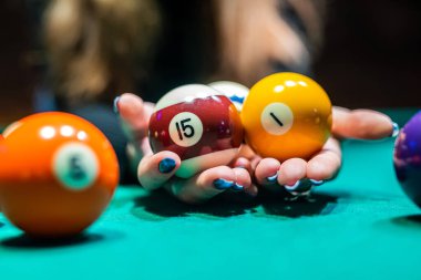 Bilardo salonundaki geniş bir masada bilardo toplarını kovalayan genç ve güzel bir kızın elleri. Bilardo konsepti