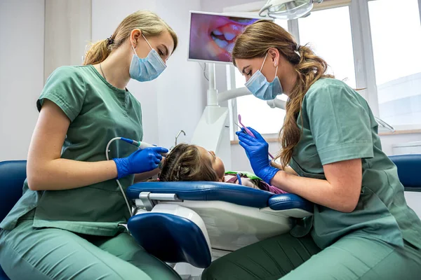 Nitelikli dişçiler çocukların dişlerini yeni profesyonel ekipmanlarla kontrol ediyorlar. Çocukların dişlerini kamerayla incelemek.