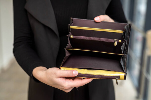 stylish lady in a black classic suit holds an open empty wallet in her gentle hands. Empty wallet concept