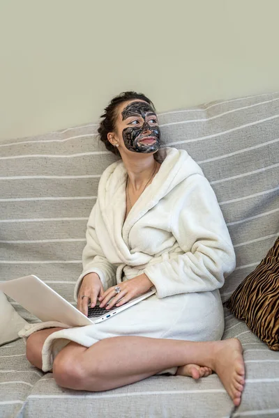 Beyaz önlüklü genç ve güzel bir kadın deriyi temizlemek için maske yaptı. Yüz bakımı kavramı