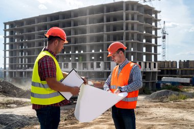 Özel giyimli ve üniformalı iki genç işçi inşaat alanında bir ev inşa etme sürecini tartışıyor. İnşaat konsepti