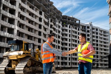 two young professionals in special uniforms and helmets agree to build new houses. The concept of a new building