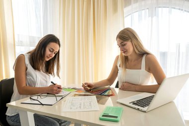 İki tasarımcı ev için mükemmel rengi tartışıyor, ev planı üzerinde çalışıyor. Ofiste apartman tasarımı projesi