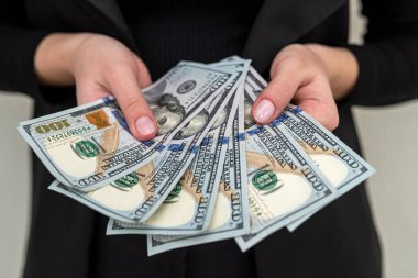 Klasik takım elbiseli güzel bir genç kız elinde yüklü miktarda para tutuyor. İş ve gelir kavramı