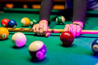 Bilardo salonundaki geniş bir masada bilardo toplarını kovalayan genç ve güzel bir kızın elleri. Bilardo konsepti