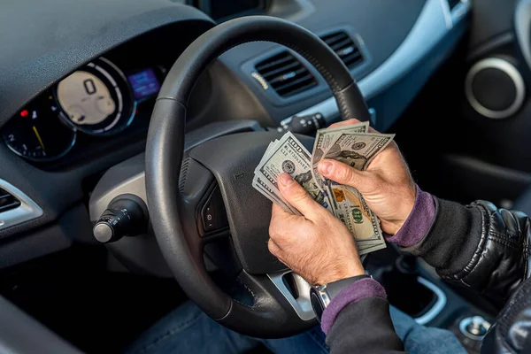 hands of a car driver holding banknotes of dollars in the middle in the car. Business concept. The concept of buying a car