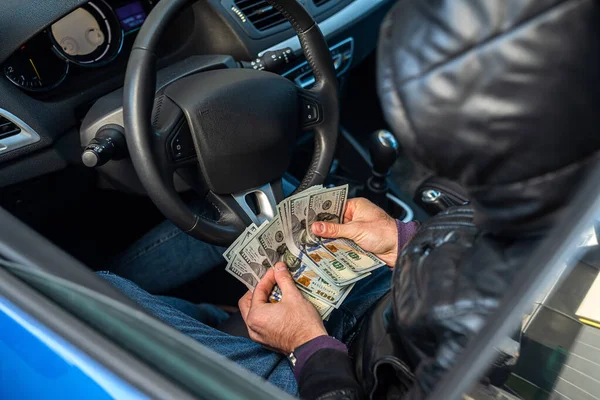 hands of a strong man holding dollar bills in the car. Car concept. Business concept