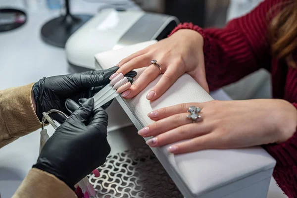 a girl who is a manicurist works on the nails of her client who went for a manicure during a pandemic. The concept of the beauty salon. Manicure concept