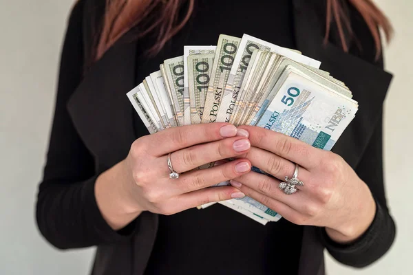 Genç kadın mutlu bir şekilde gülümsüyor, şehirde Polonya zloti paraları tutuyor. Cilalı banknotları olan başarılı kadın kavramı