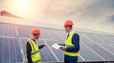 Belgeli yakışıklı delikanlılar yeni kurulmuş panellerin yanında duruyor. Yeşil elektrik kavramı