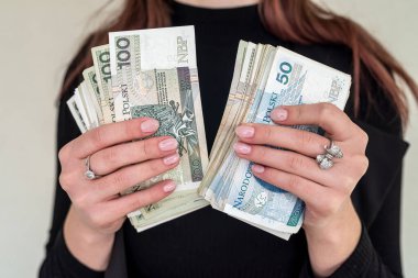 Genç kadın mutlu bir şekilde gülümsüyor, şehirde Polonya zloti paraları tutuyor. Cilalı banknotları olan başarılı kadın kavramı