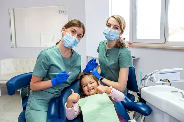 Odontoiatra Pediatrica Con Assistente Con Paziente Bambina Che Mostra Pollici — Foto Stock