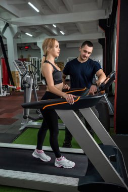 Genç bayan forma girmek ve kalifiye bir eğitmene selülitten kurtulmak için spor salonuna geldi. Erkek koçla antrenman yapma kavramı.