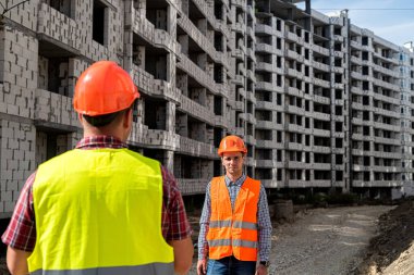 Özel üniformalı ve kasklı iki genç profesyonel yeni evler inşa etmeye karar verdi. Yeni bir bina konsepti