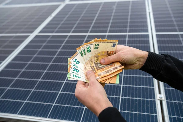 beautiful young hands in black hold a large sum of euros paid for solar panels. Green electricity concept