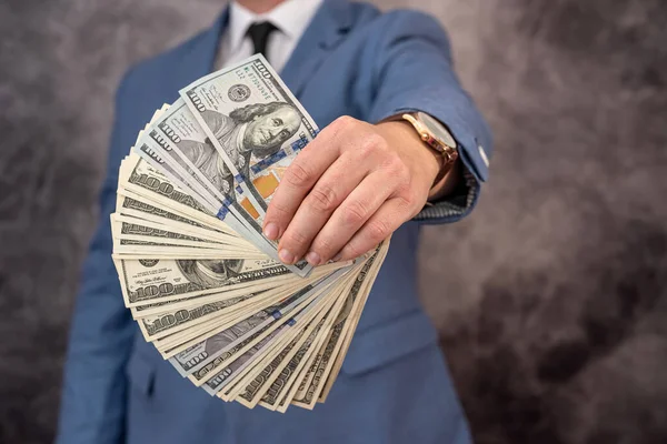 Closeup of hands of a businessman in suit giving cash money us dollars