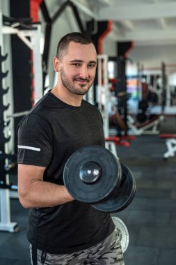 Genç beyaz bir adam spor salonunda dambıllarla antrenman yapıyor. etkin yaşam biçimi