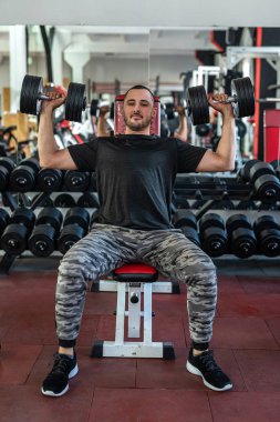 Genç sporcu spor salonunda dambılla egzersiz yapıyor. ağırlık egzersizleri konsepti