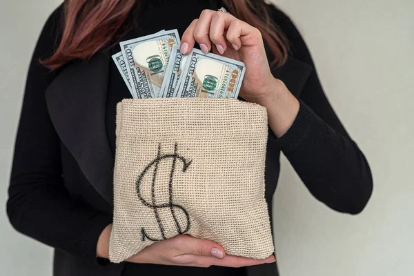 young serious girl in elegant stylish clothes holding earned dollar bills. The concept of earned money