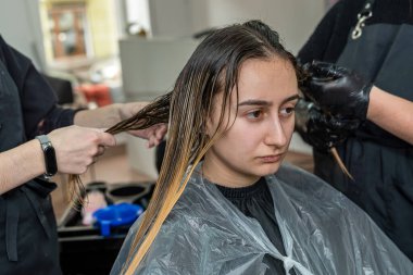 Genç ve güzel bir müşteri güzellik salonundaki bir sandalyede oturuyor ve saçları en iyi renkli ressamlar tarafından boyanmış. Renkçi sihirbaz konsepti