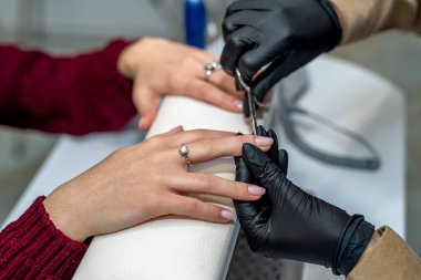 Yeni salonda, bir tırnak uzmanı salgın sırasında düzenli bir müşteri için jel cilası yapıyor. Manikür konsepti. Jel vernik kaplama kavramı