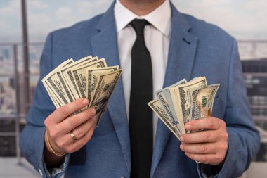 Takım elbiseli adam bize dolar, tasarruf ve finans konsepti sayıyor.