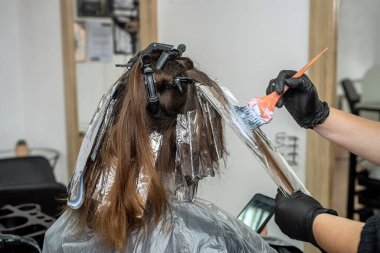 Bir salgın sırasında, kabinde maske takmış güzel siyah saçlı bir kız resmediliyor. Salonda salgın sırasında saç boyama konsepti