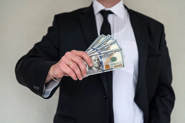 Closeup of hands of a businessman in suit giving cash money us dollars