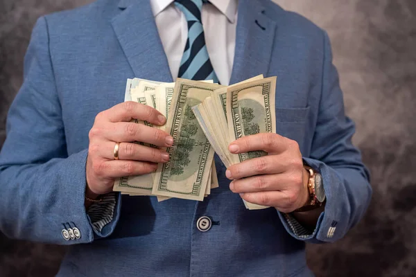 Man in blue suit count stack of dollar bills. Business concept