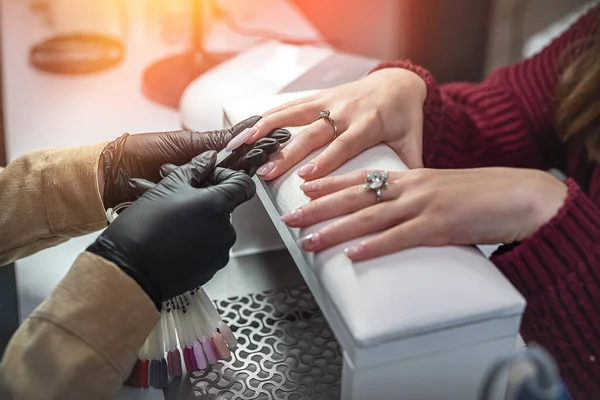 Manicure master with client in beauty salon chooses color of gel polish. Manicure concept