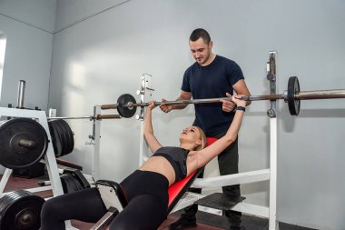 Spor salonunda genç, zayıf kadın müşteriyle çalışan kişisel erkek antrenör. Öğretmen sporcuya yardım eder.
